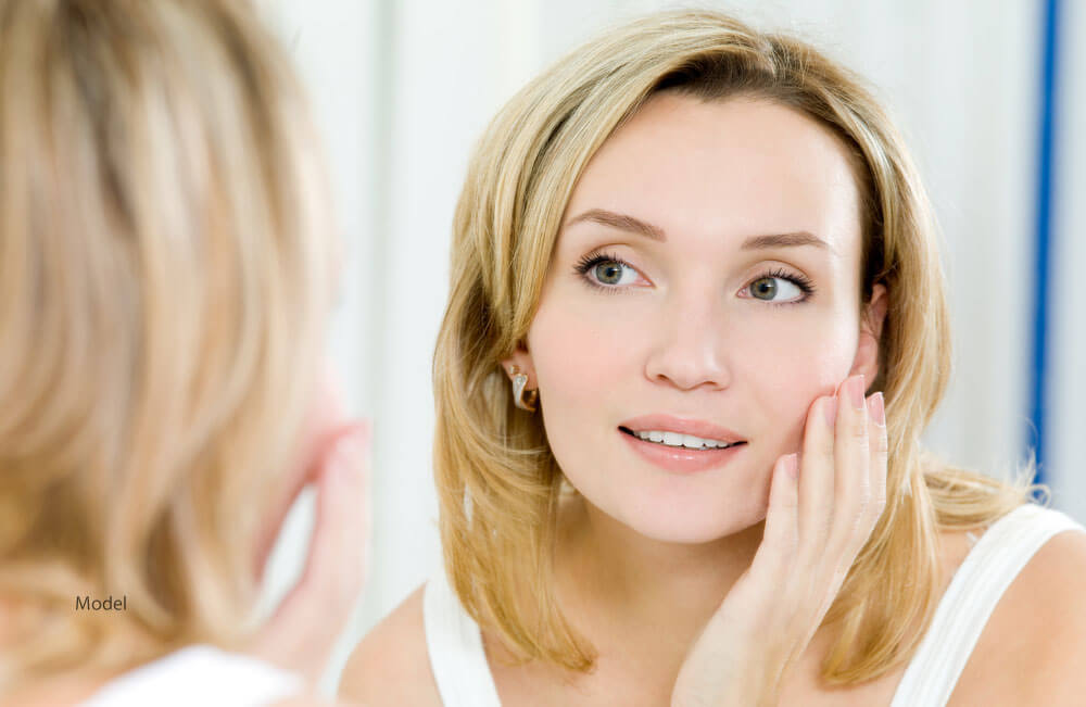 woman looking at a mirror after facelift surgery