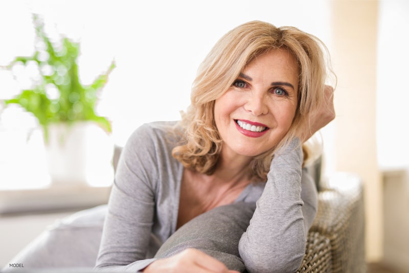 Woman sitting at home, smiling on her couch