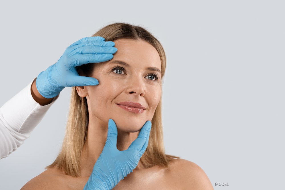 A doctor examines the face and skin of a blonde woman.