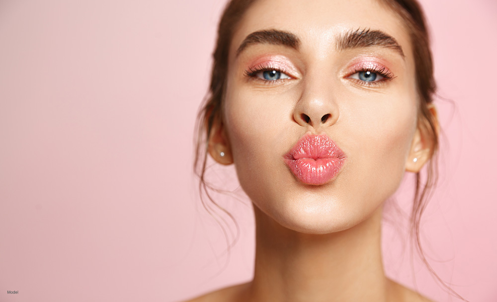 Woman with pink lipstick blowing a kiss