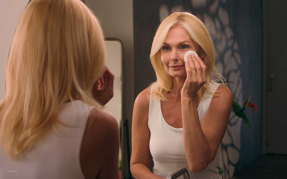 Mature woman applying makeup in a mirror