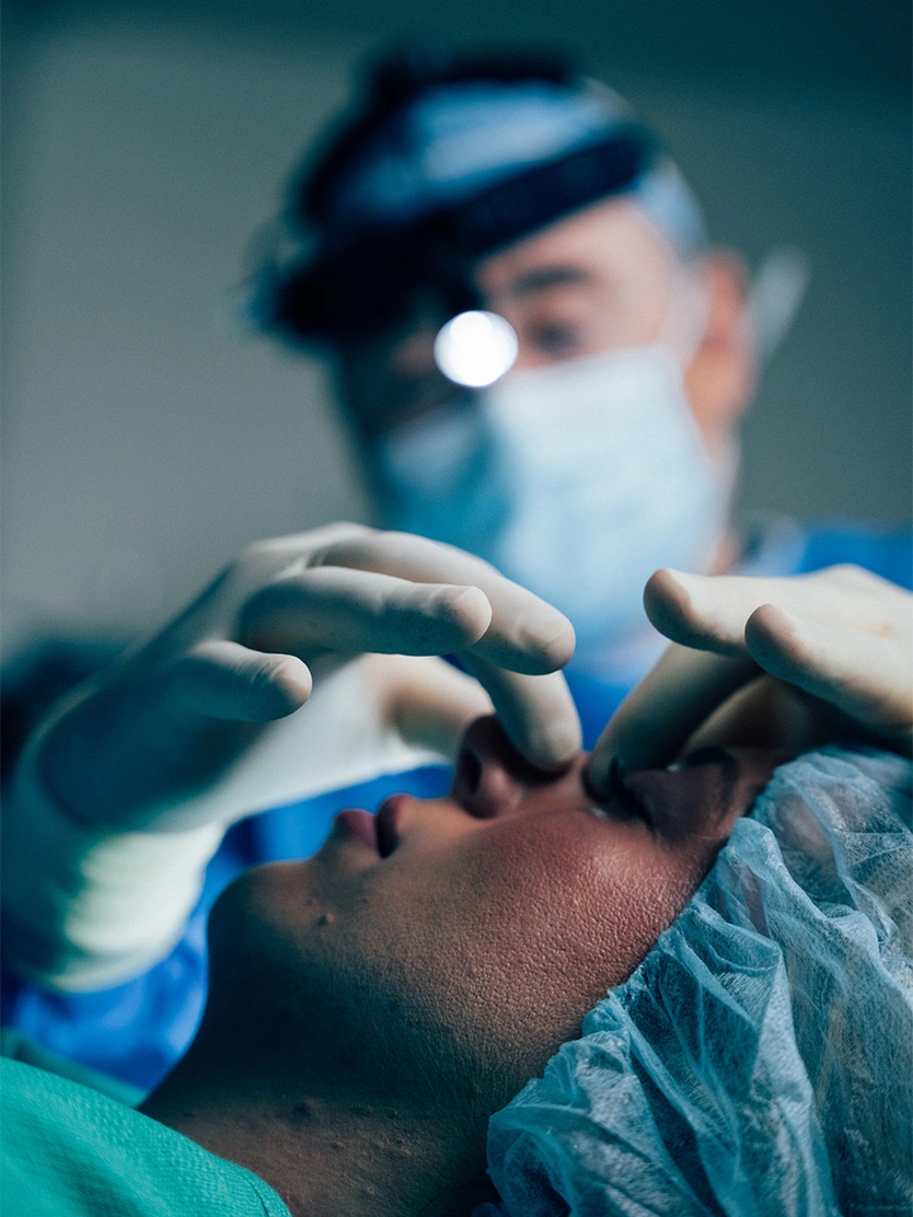 Surgeon Ackerman MD performing facial plastic surgery procedure on patient in operating room - Rhinoplasty in Newport Beach, CA