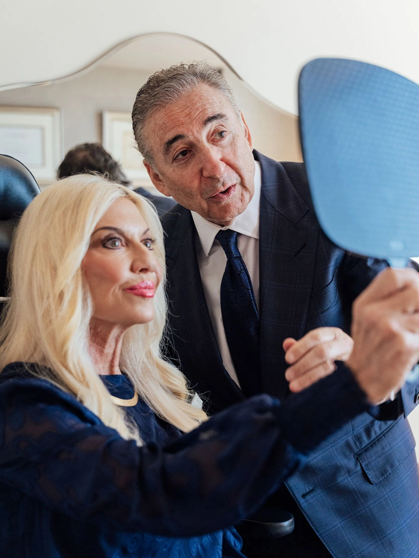 Boris M. Ackerman, MD and patient in navy suits reviewing face together in modern office setting - Vertical facelift in Newport Beach, CA