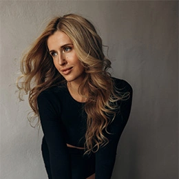 Woman with long wavy blonde hair wearing black top showing natural beauty and smooth skin for dermal filler treatment - Botox in Newport Beach, CA