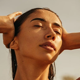 Woman with glowing skin touching face after chemical peel treatment showing smooth complexion and radiant results - Laser skin resurfacing in Newport Beach, CA