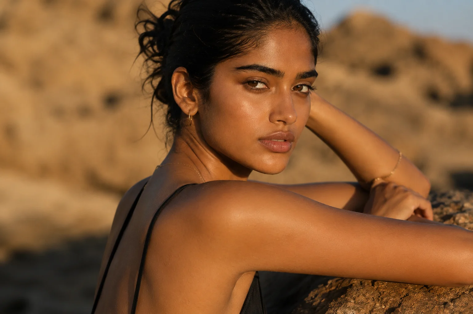 Woman with dark hair posing outdoors in golden hour light against desert landscape background - Chemical peels in Newport Beach, CA