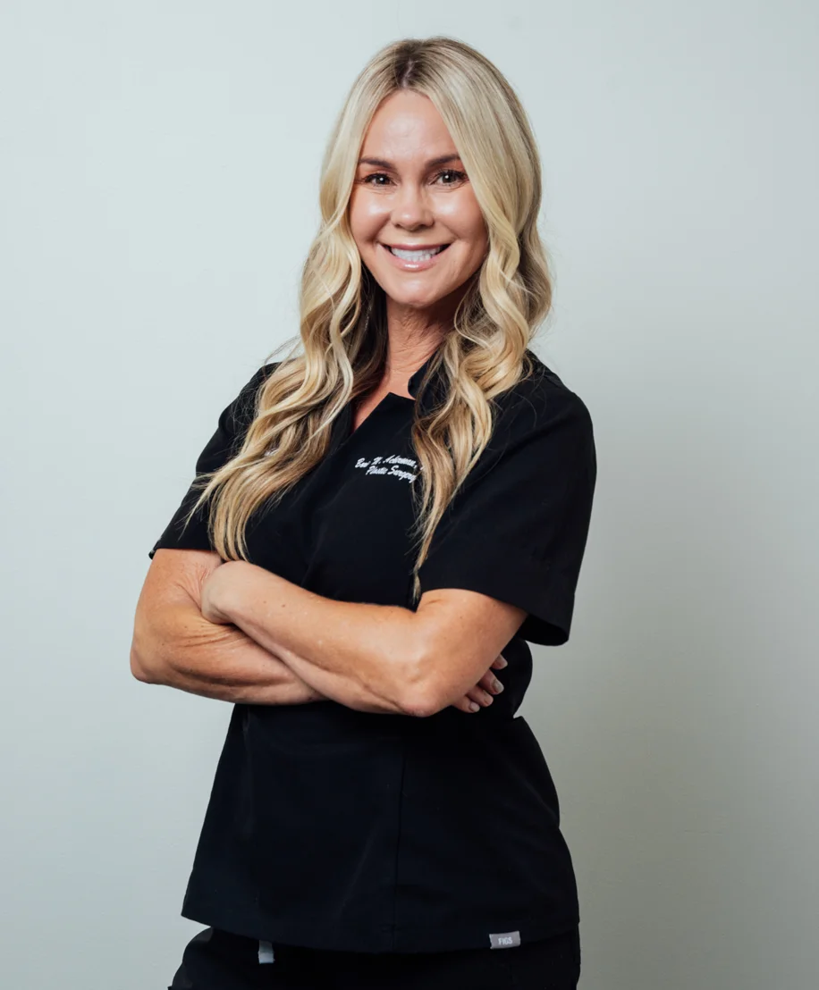 Ashley in black polo uniform smiling with arms crossed against gray background