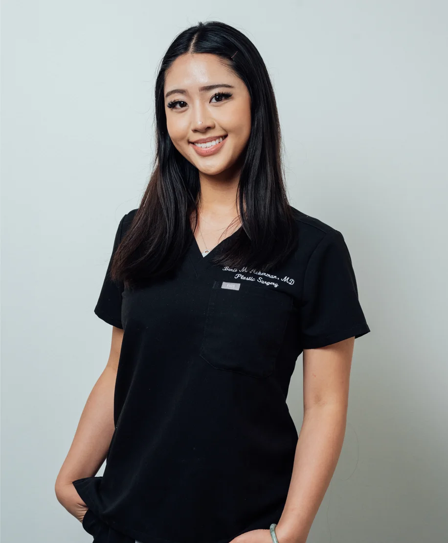 Professional staff member in black medical scrubs smiling at camera against gray background
