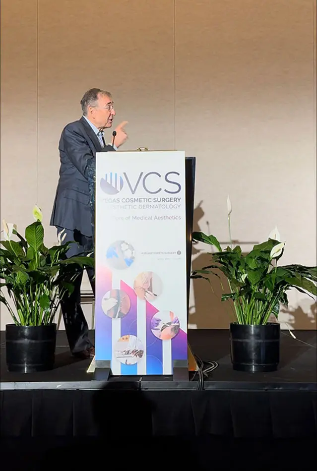 Dr Boris M Ackerman MD presenting at IVCS podium with company banner and green plants on stage